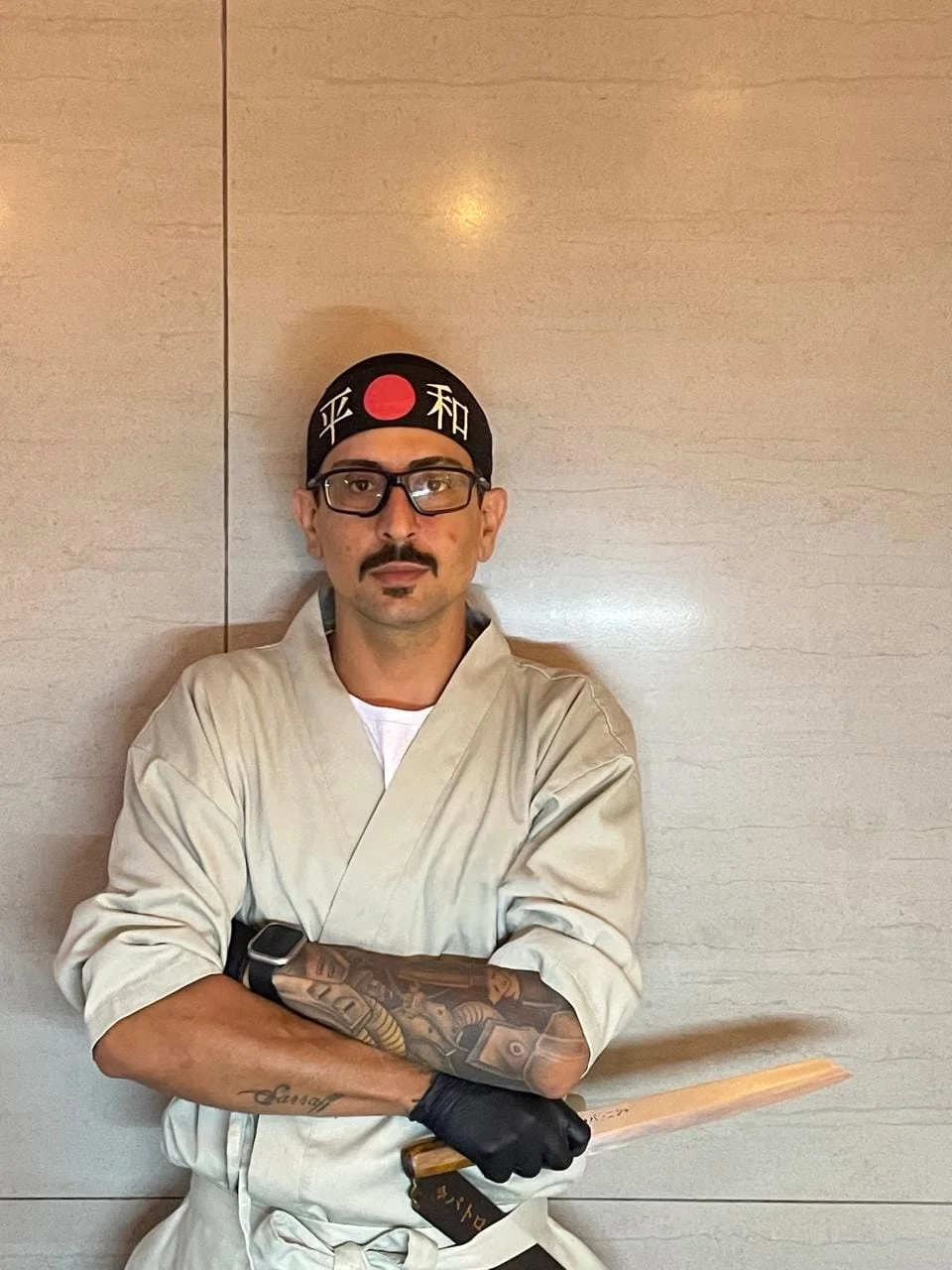 Chef Matheus Sarraff de braços cruzados, com bandana japonesa e uma faca de sushi